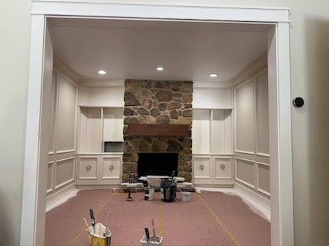 Built-in cabinetry masked and prepped before painting, stone fireplace visible